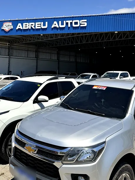 Picapes no pátio, em frente ao letreiro da Abreu Autos