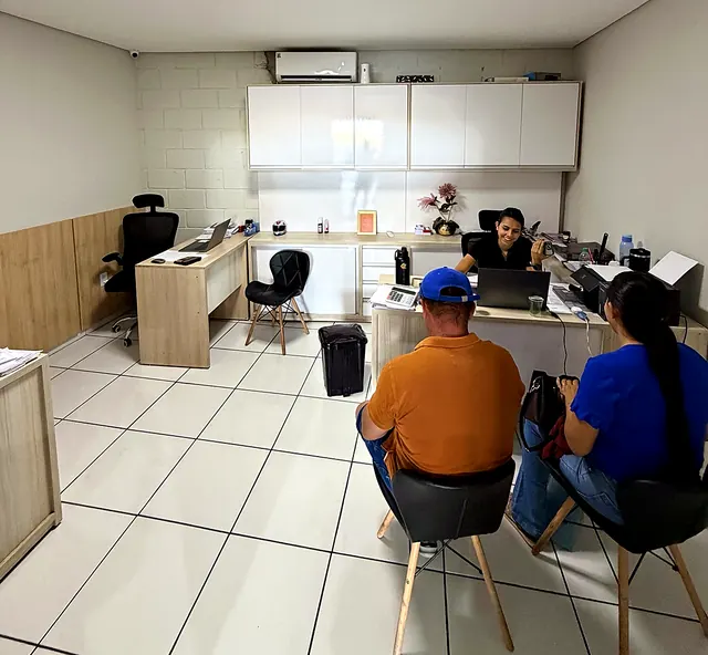 Atendente da Abreu Autos conversando com um casal de clientes na sala de atendimento